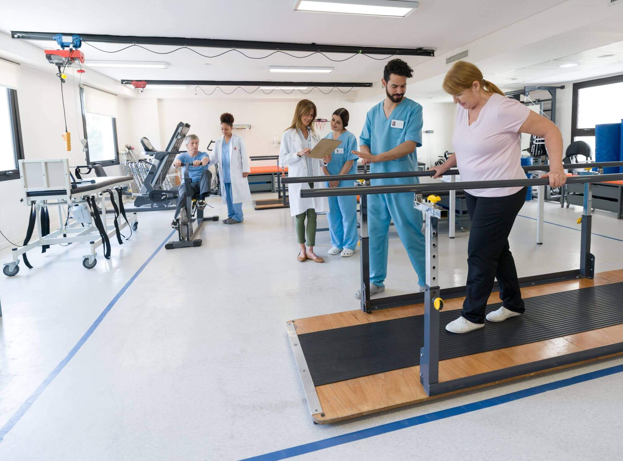 Physical therapy session with elderly woman and healthcare professionals.