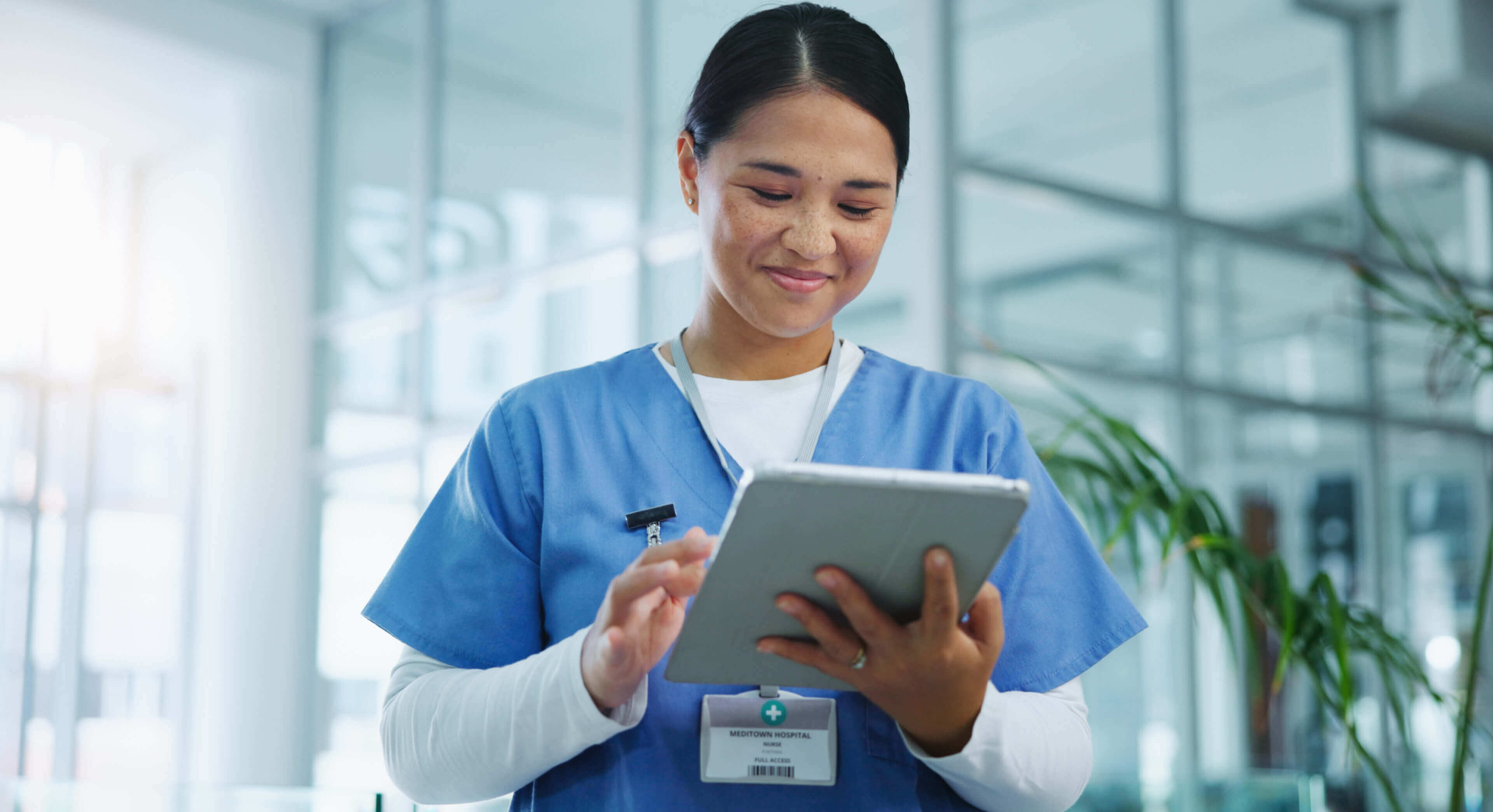 Healthcare worker using a tablet in a medical facility.
