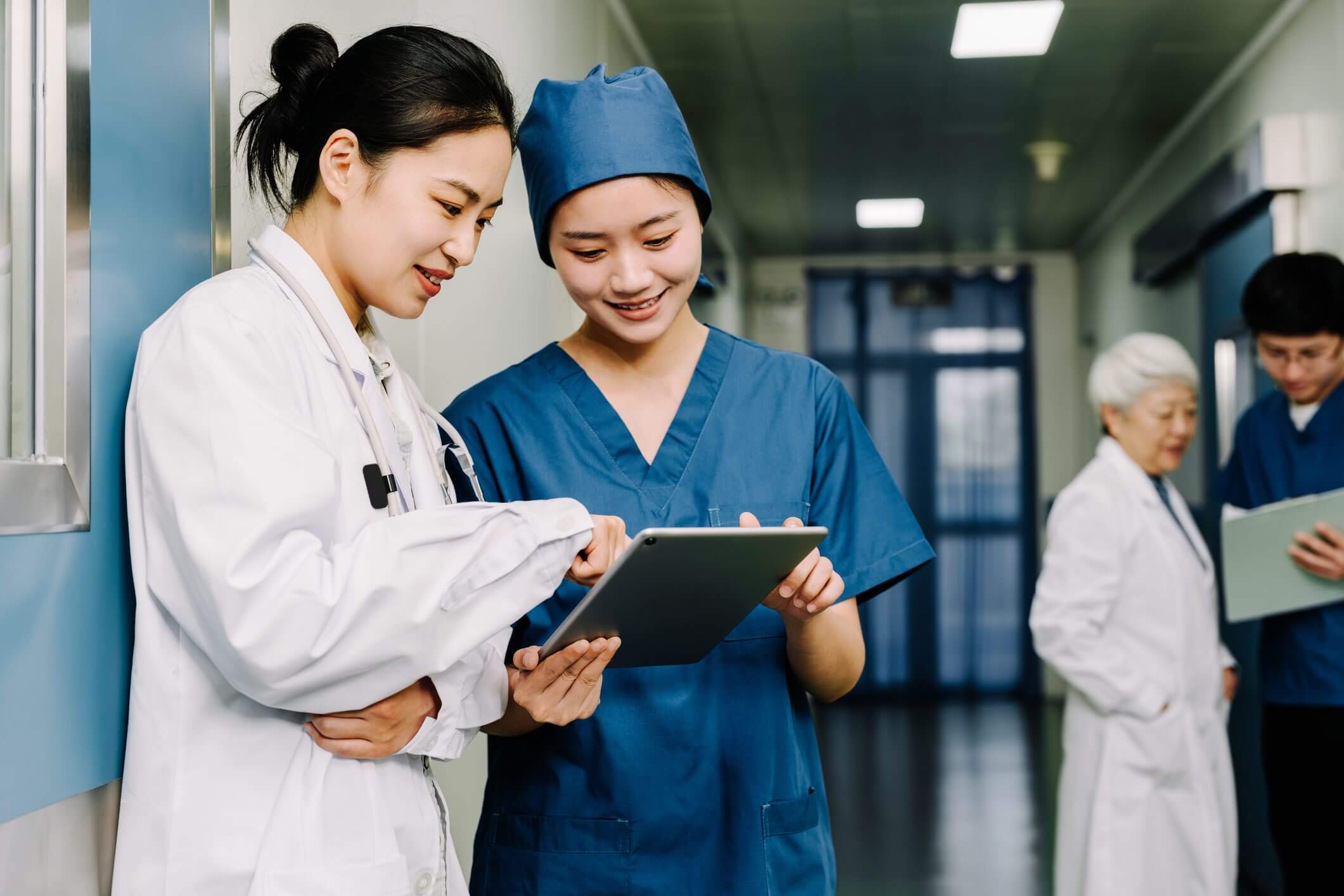 Two medical professionals discussing patient information on a tablet.