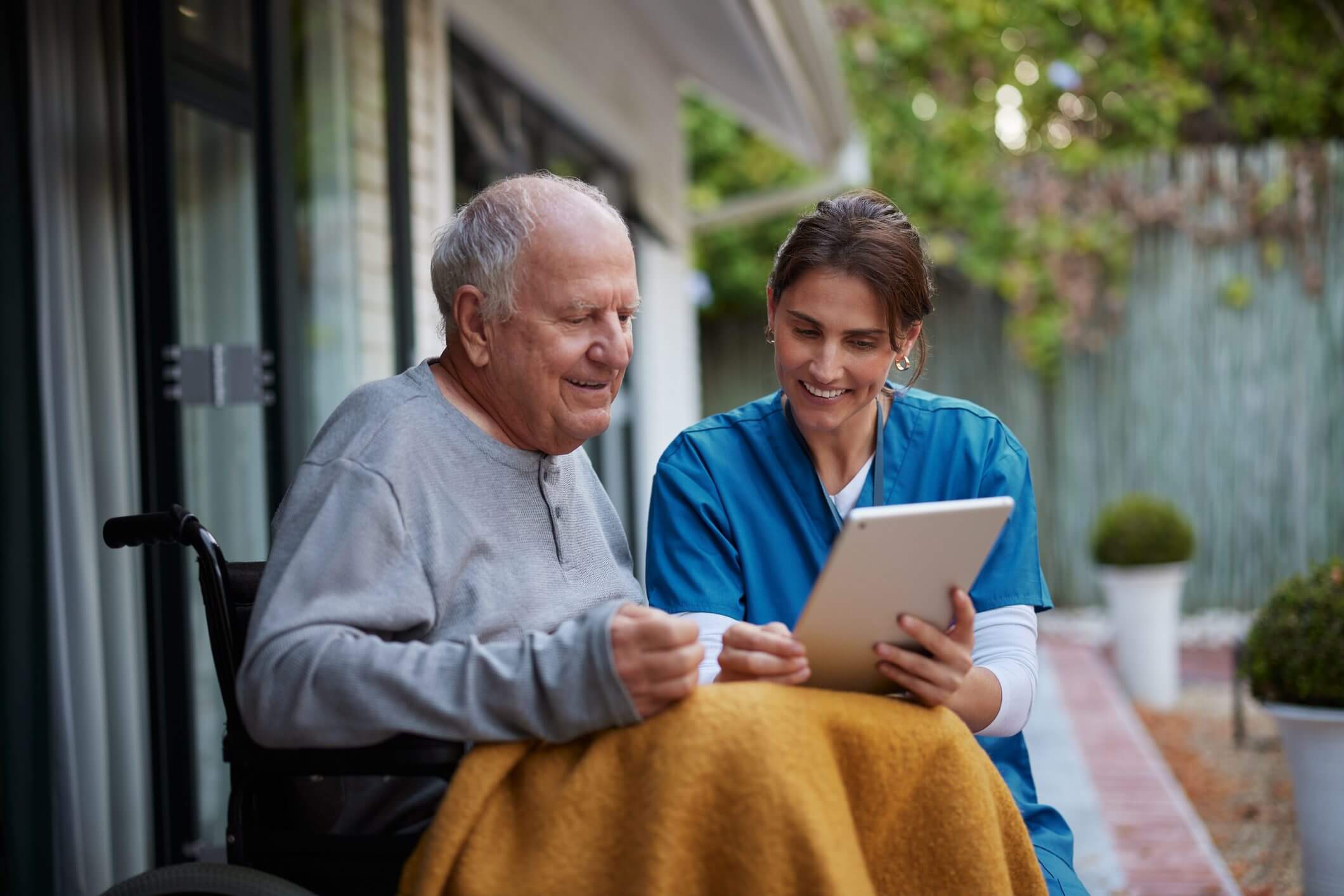 Elderly man and caregiver sharing a joyful moment outdoors.