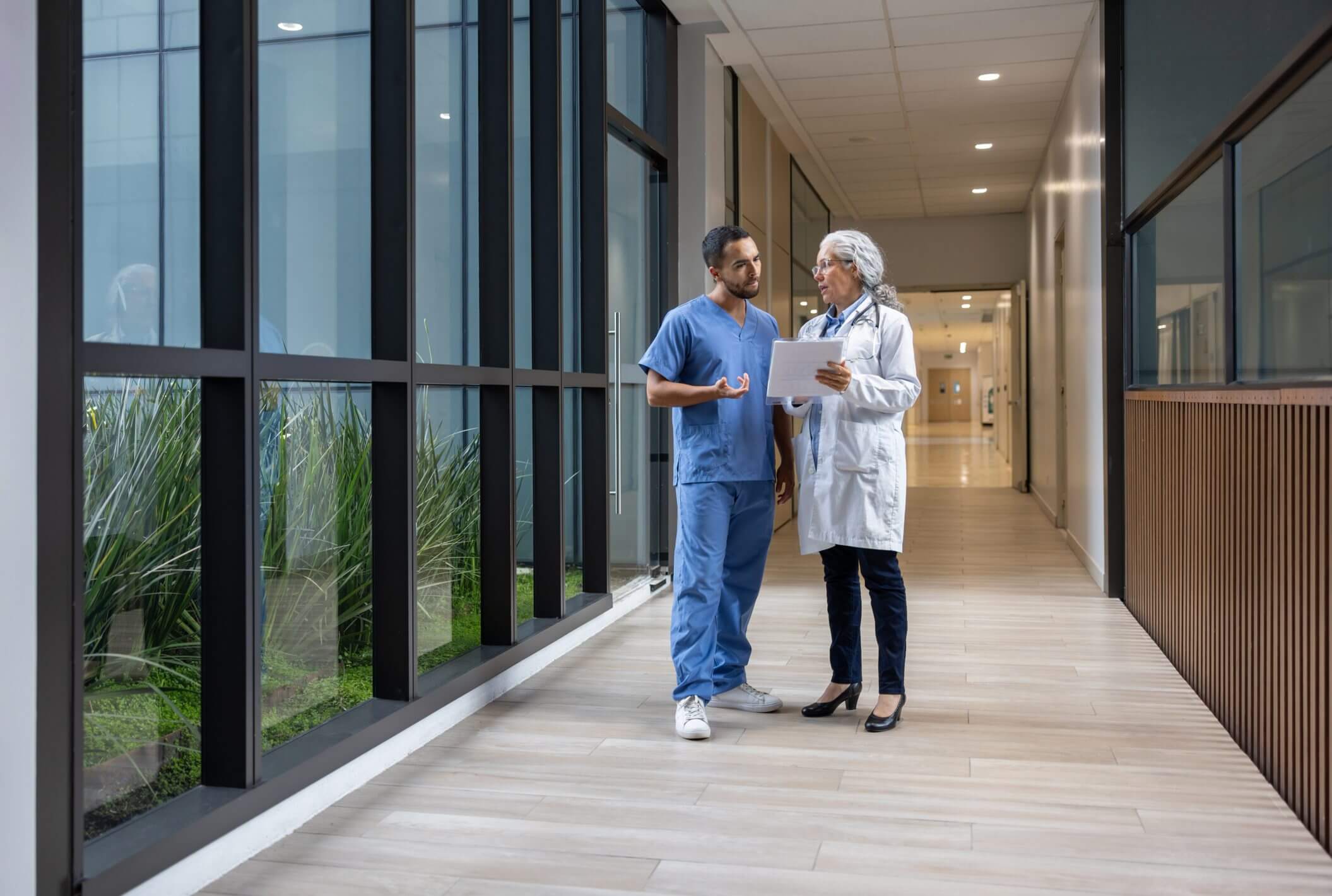 Two healthcare professionals walking and talking in a hospital corridor.